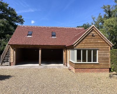 Front view of the newly built cartlodge and studio with a red-tiled roof, timber cladding, and large windows.