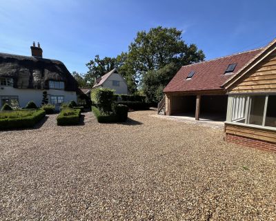 Close-up of the cartlodge and studio with gravel driveway in the foreground, highlighting the structure’s modern features.