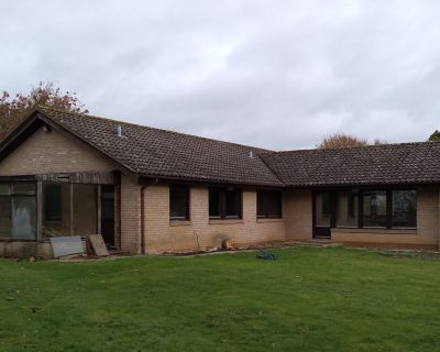 Rear view of the 1980s bungalow before renovation, showing an old conservatory and dated brickwork.
