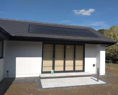 Side entrance of the refurbished bungalow, showcasing new solar panels and modernised design.
