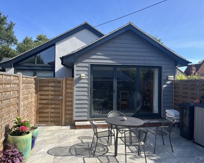 Rear view of the dining room extension with grey cladding and folding sliding doors opening to a patio.